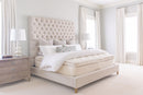 Neatly made bed with a tufted headboard in a bright bedroom.